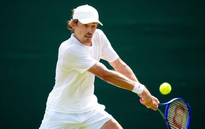 Alex de Minaur playing a two-handed backhand on grass