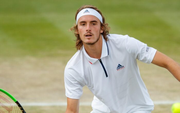 Stefanos Tsitsipas moves forward to play a shot during a grass-court match