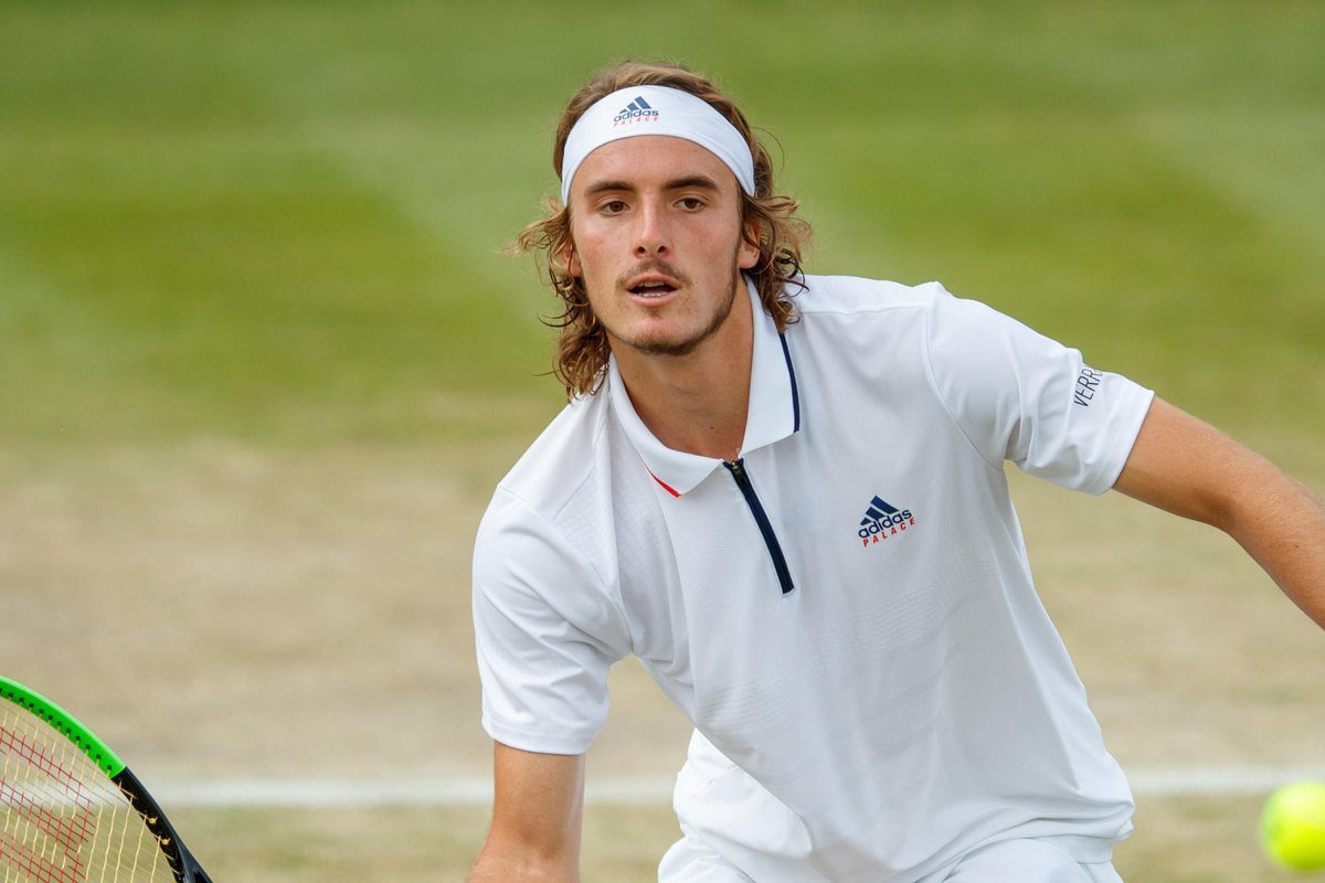 Stefanos Tsitsipas moves forward to play a shot during a grass-court match