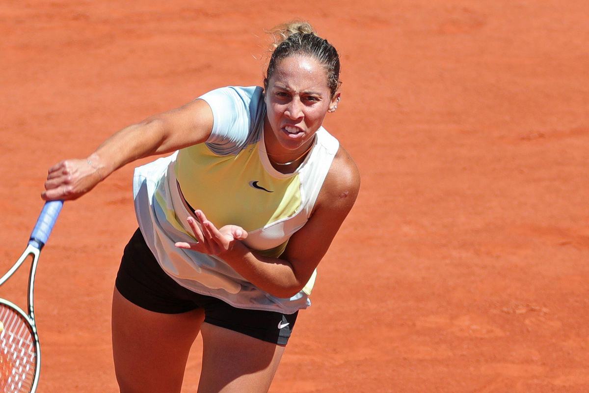 Madison Keys striking a forehand on a clay court in a white and blue top