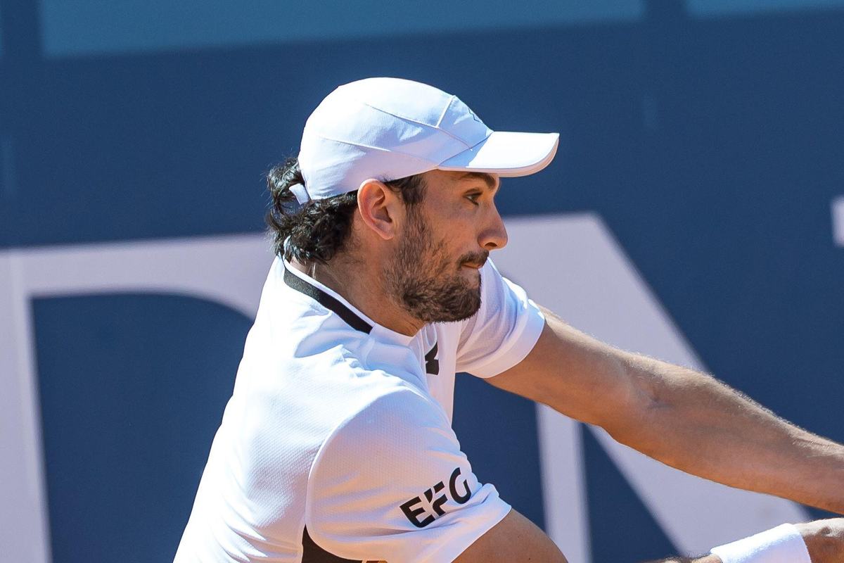 Valentin Vacherot playing a backhand in a white shirt and white cap