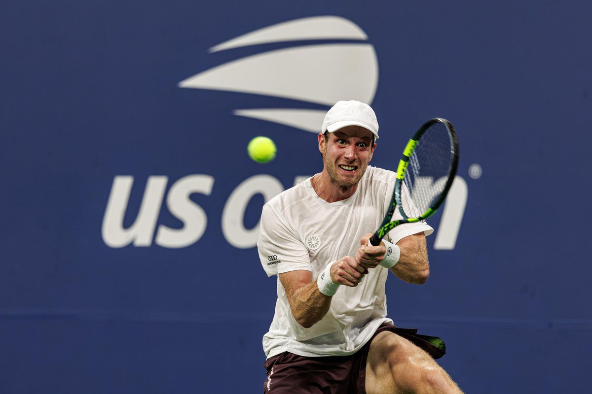 Botic van de Zandschulp plays a backhand in front of a US Open backdrop
